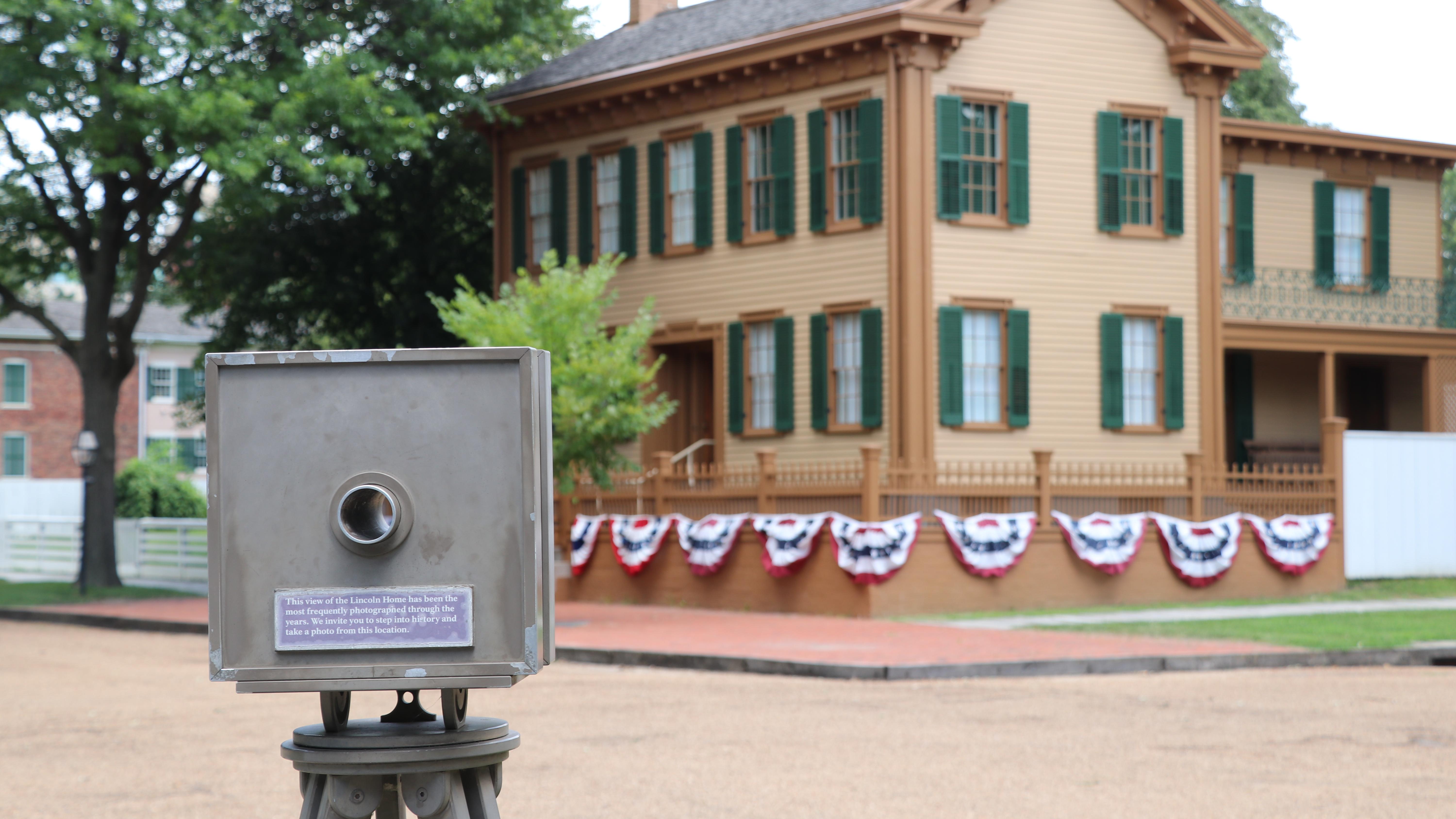 An example of a historic camera pointing toward the two-story Lincoln Home which has patriotic bunti