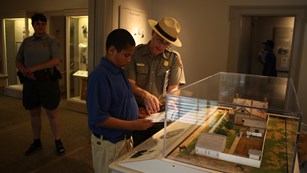 Photo of park ranger showing student a pamphlet in front of exhibit of Lincoln Home