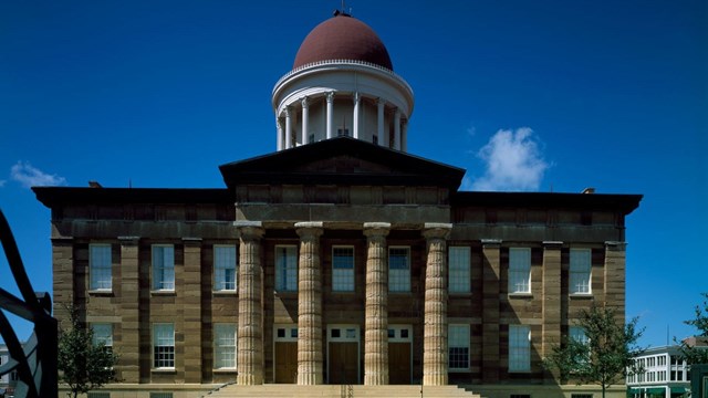 Illinois Old State Capitol: Large 2 story building of sand-colored stone with pillars & red dome