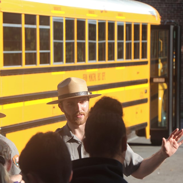 Two rangers standing in front of a group of students before their field trip. 