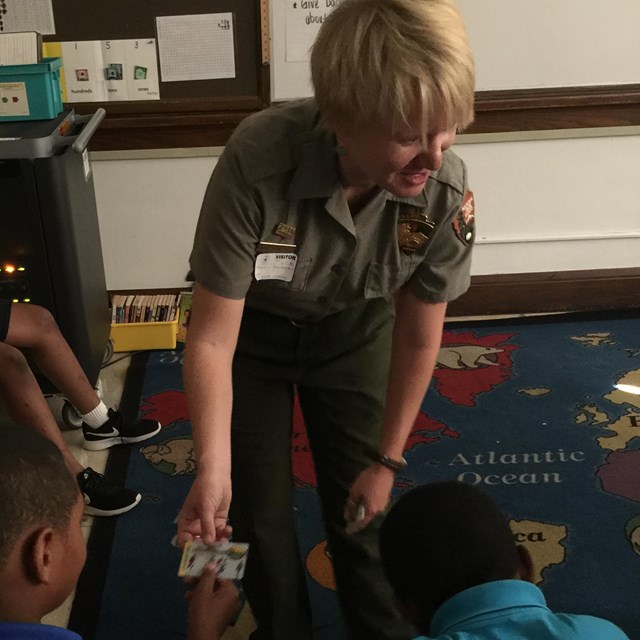 A ranger hands out a Every Kids Outdoor pass to a student