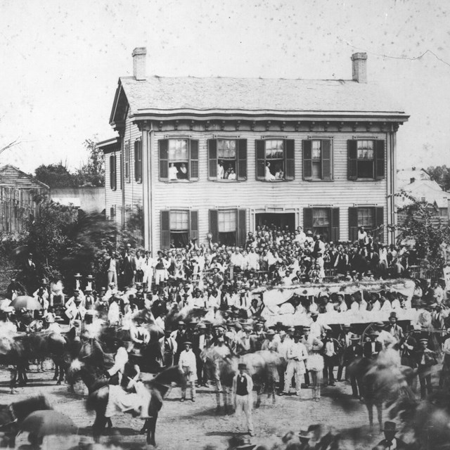Photo of republican rally in front of Lincoln Home. A large crowd of people stand in the street.