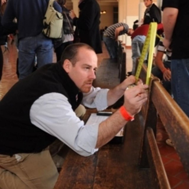 A teacher measures a bench with students