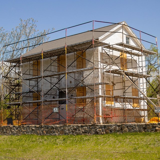 Preservation crews begin erecting scaffolding around the house to access the roof and upper levels f