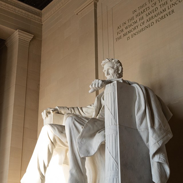 A large statue of Abraham Lincoln inside a tall room with columns.