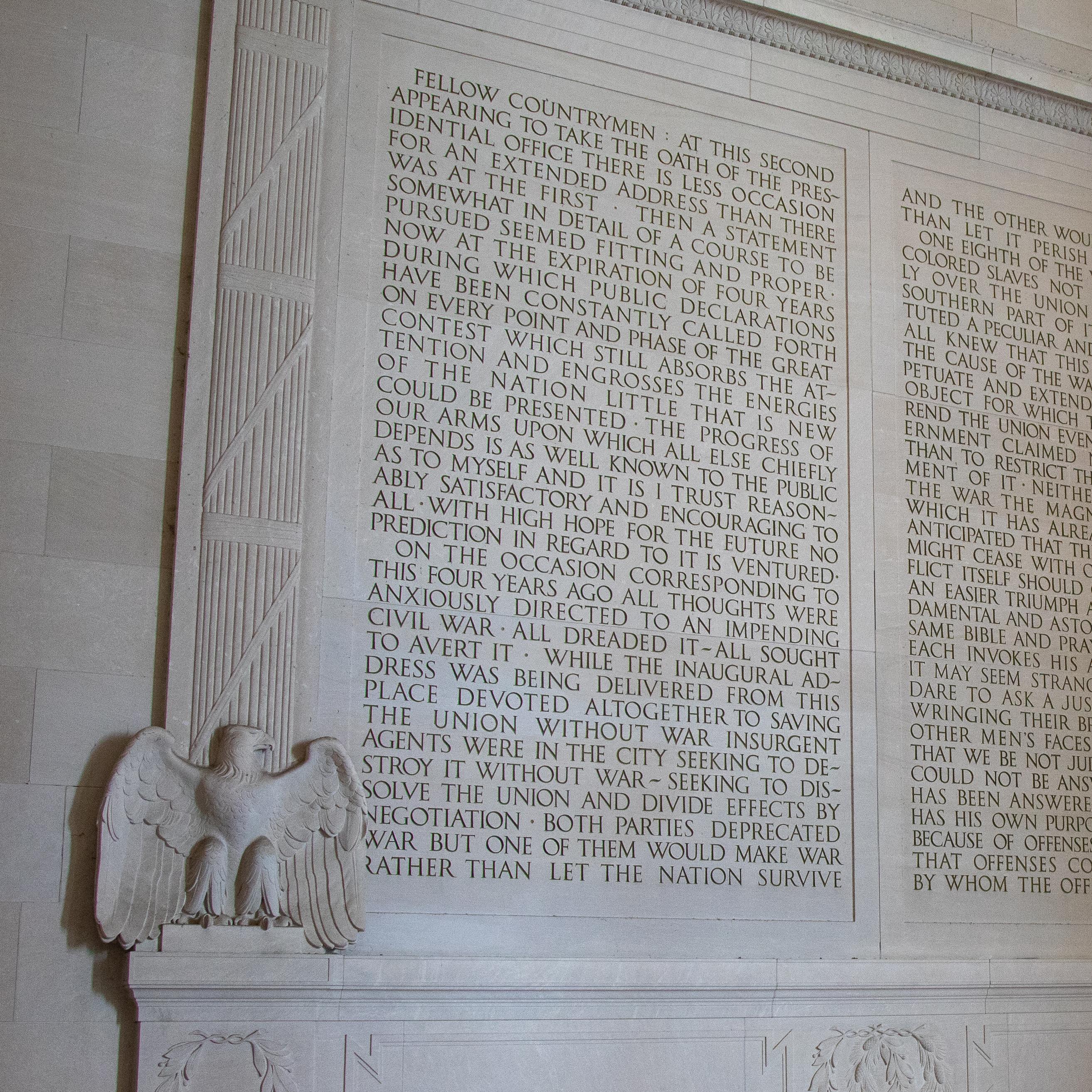 A wall of text carved into the stone, flanked by eagles.