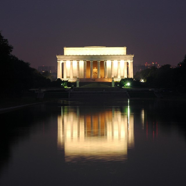 The Lincoln Memorial lit up at night reflecting on the water.