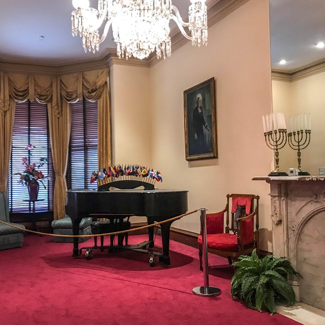 Parlor that includes a piano covered with international flags and a portrait of Mary McLeod Bethune