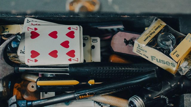 Tool box full of different small items like playing cards, fuses, and pencils