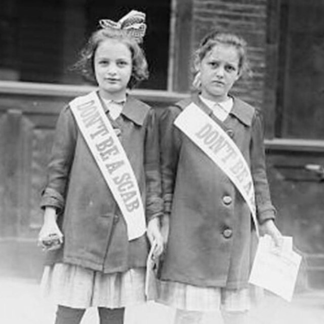 Black and white photo of two young girls standing next to each other hearing sashes