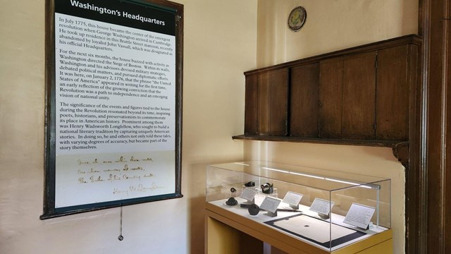 Room in historic house with exhibit cases of books and clothing