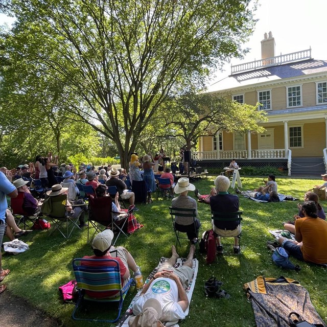 Crowd seated on chairs and blankets on lawn to watch concert