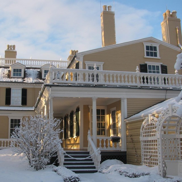 An exterior view of the Longfellow House with snow during winter.