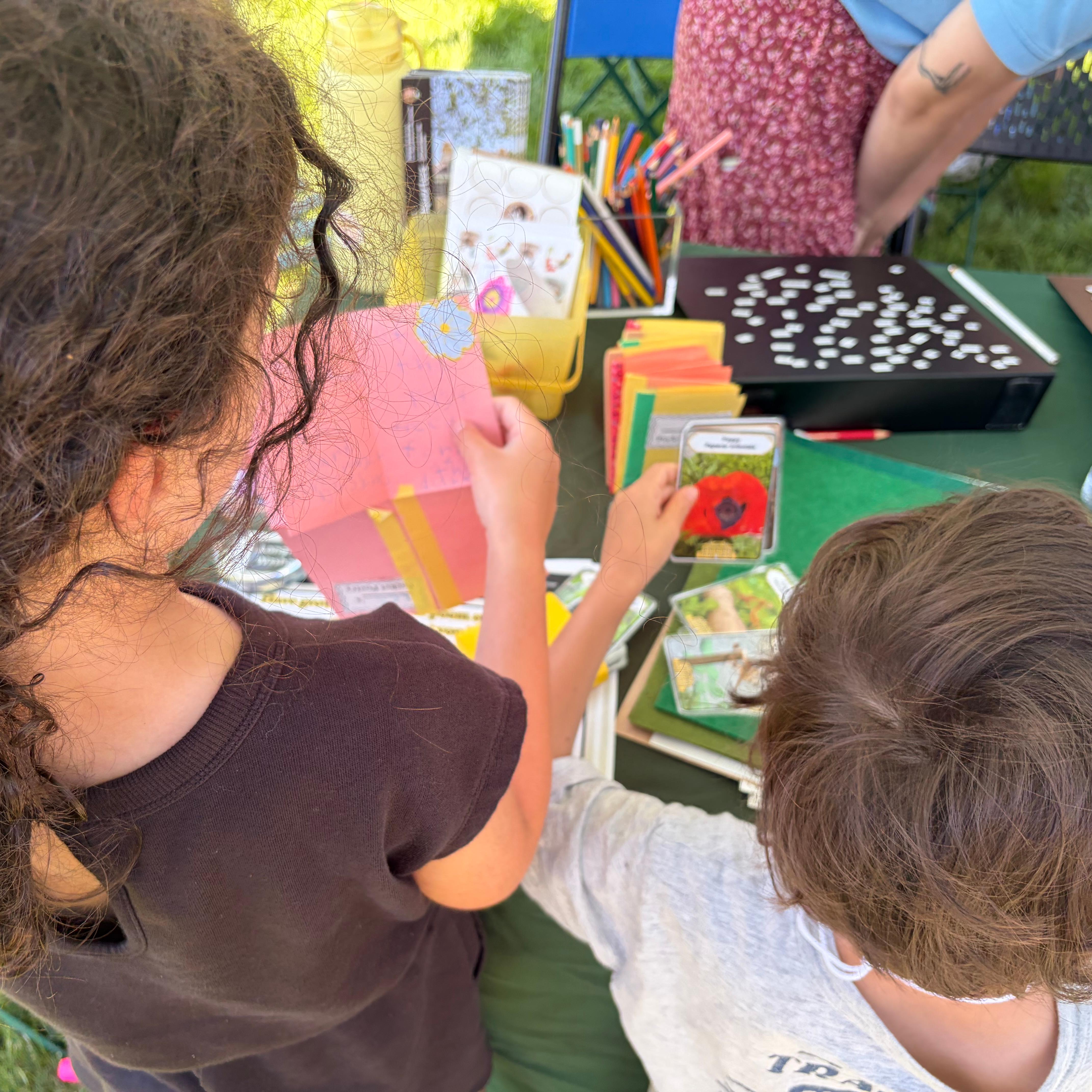 Two children explore an activity table with crafts and nature cards