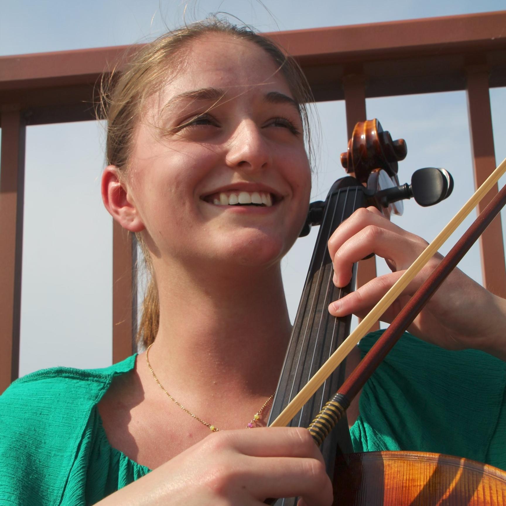 Woman outdoors holding a cello