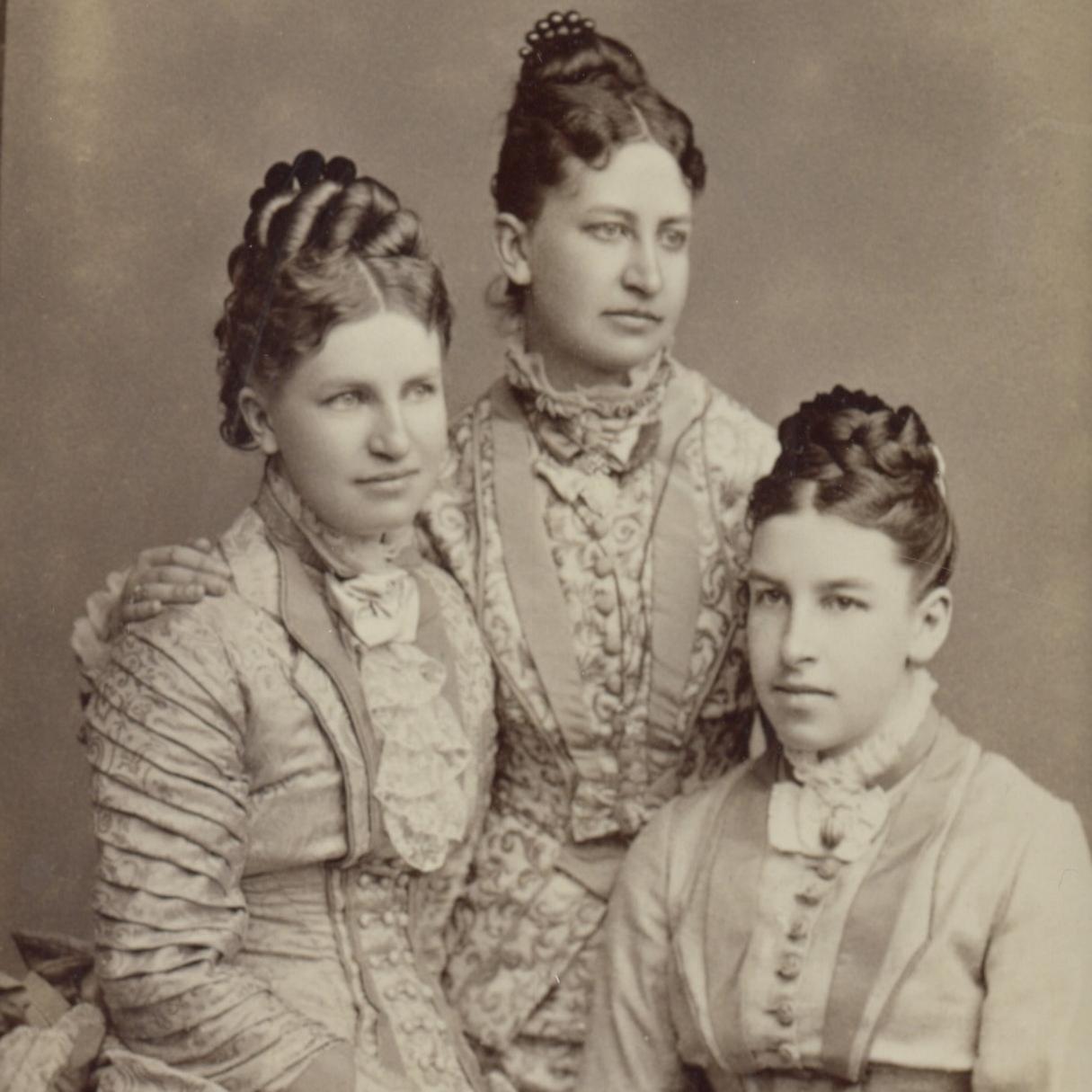 Seated portrait of three white woman with dark hair.