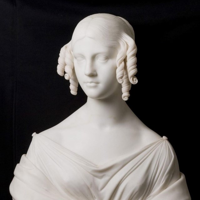 White marble bust of young woman with corkscrew curls