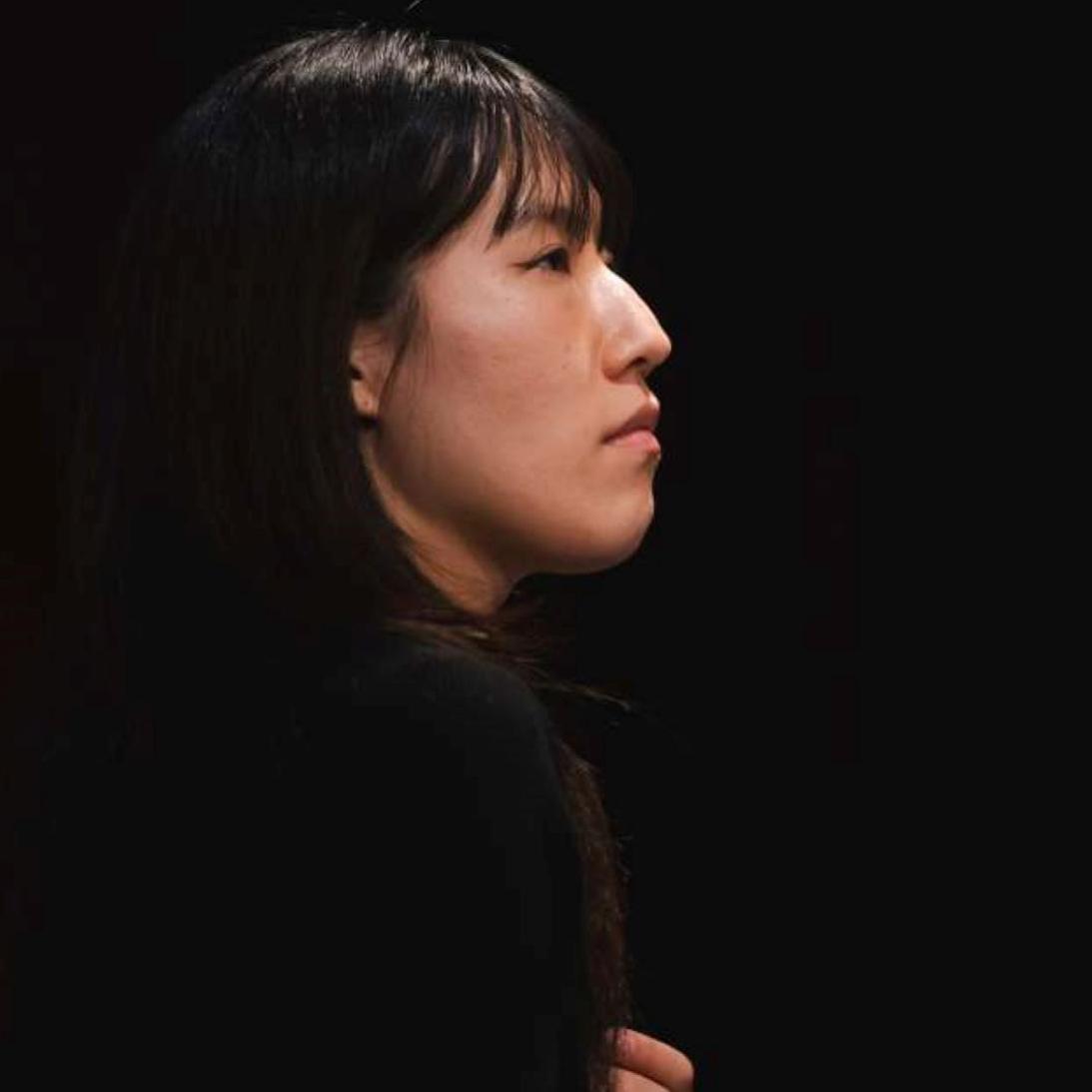 Yujin Han in profile with a black background.