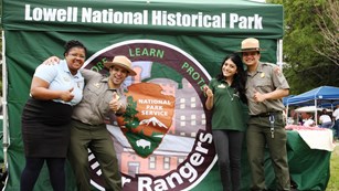 A group of rangers and interns pose for a fun photo by a National Park Service tent