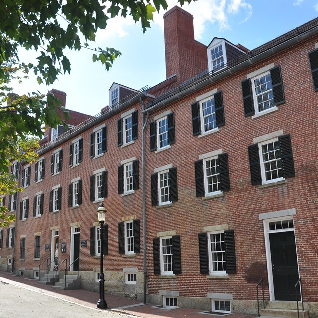 the exterior of a red brick building with a walkway and park in front