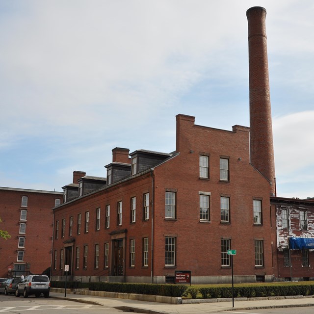 Brick Building with a smokestack rising up behind it