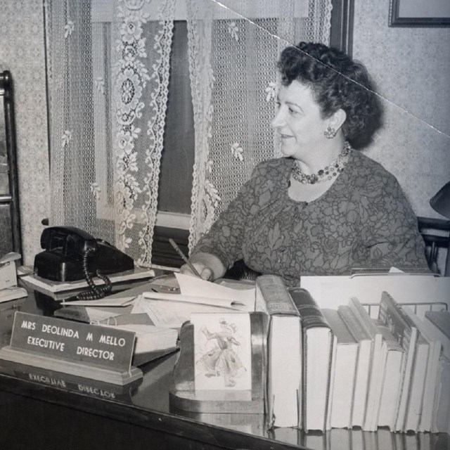 Deolinda Mello sits at her desk in Lowell