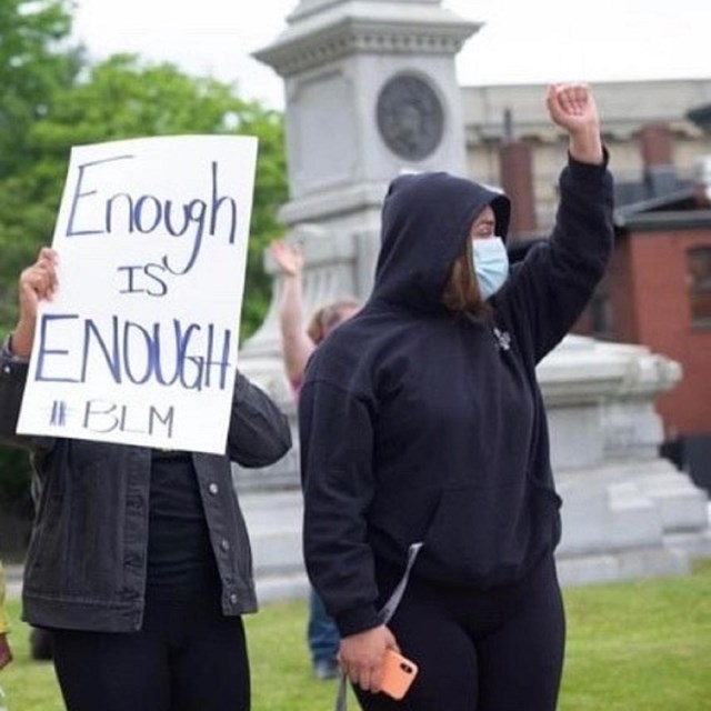 Demonstrators hold a Black Lives Matter sign in front of the Ladd and Whitney Monument in June 2020