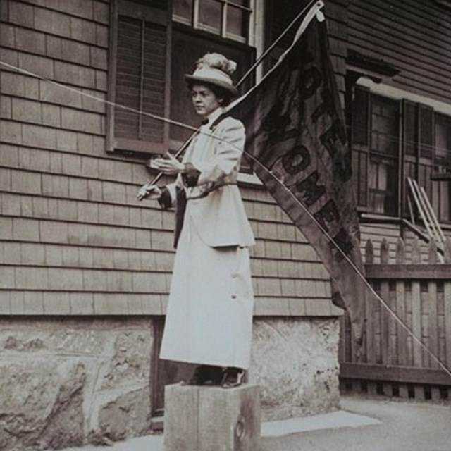 Florence Luscomb standing on top of a moxie box demonstrating for woman suffrage.