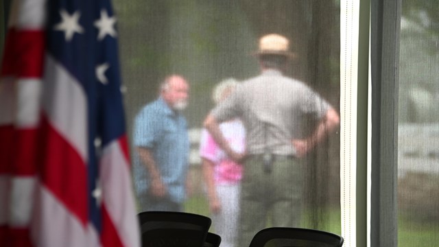 American flag with Park Ranger talking with visitors