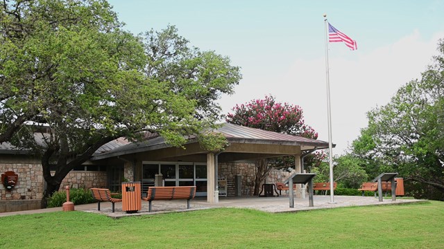 Stone building with benches and a flagpole.