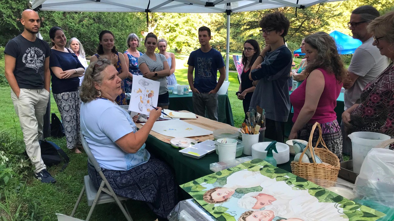 person shows watercolor painting to large group