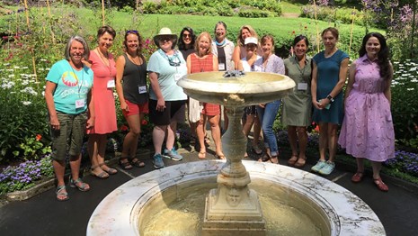 Art Educators stand around the fountain in the formal garden