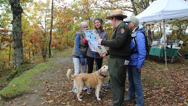 Park Ranger points out sections of trail map to visitors with dog