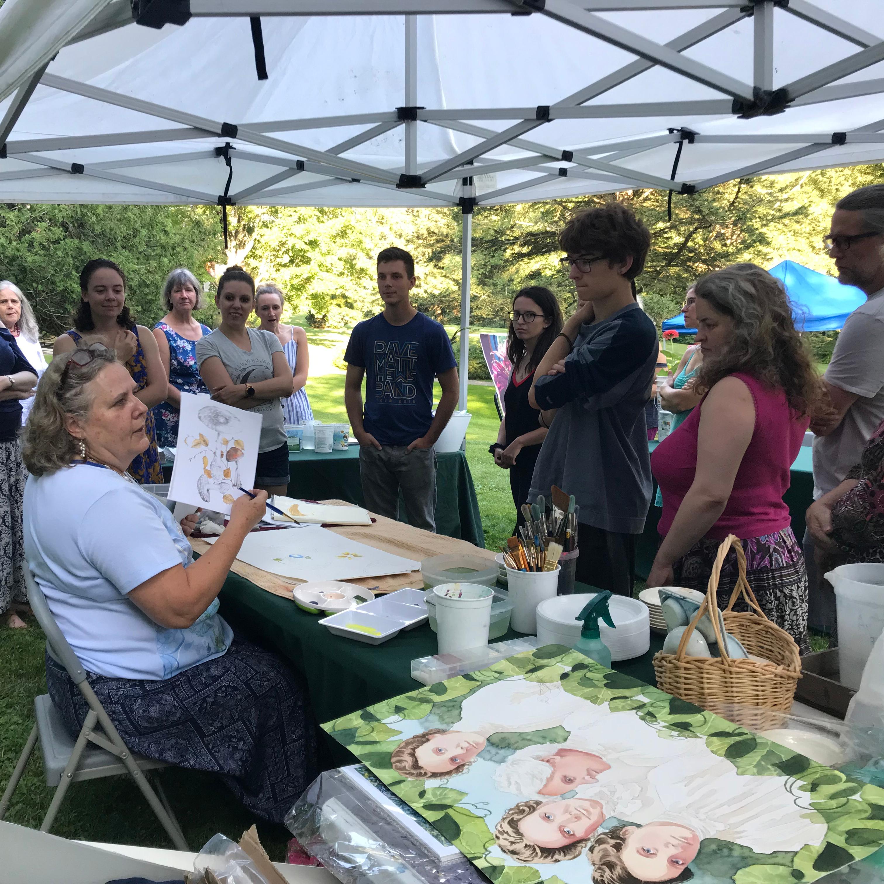 person shows watercolor painting to large group