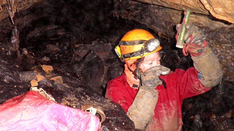 A cave researcher takes a measurement in the cave. 
