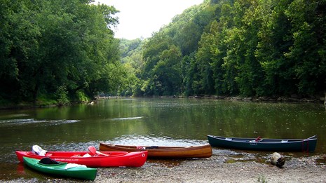 Four canoe sitting on a gravel bar along the river.