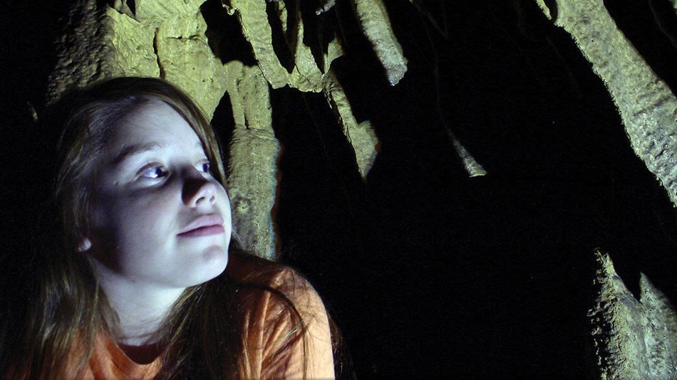 A girl looks into the cave shadows, anticipating her cave tour.