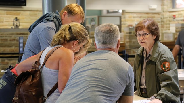 Inside the Mammoth Cave Visitor Center, a ranger answers visitors' questions at the info desk.