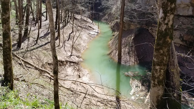 A sinkhole filled with blue green water.