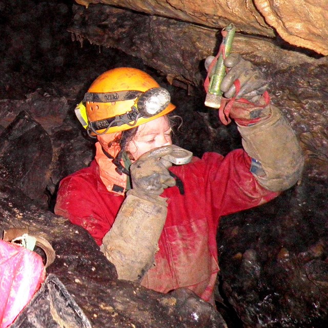 A cave researcher takes a measurement in the cave. 
