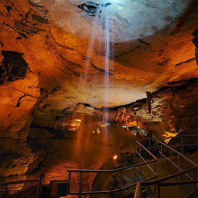 A waterfall enters the cave from the ceiling. 