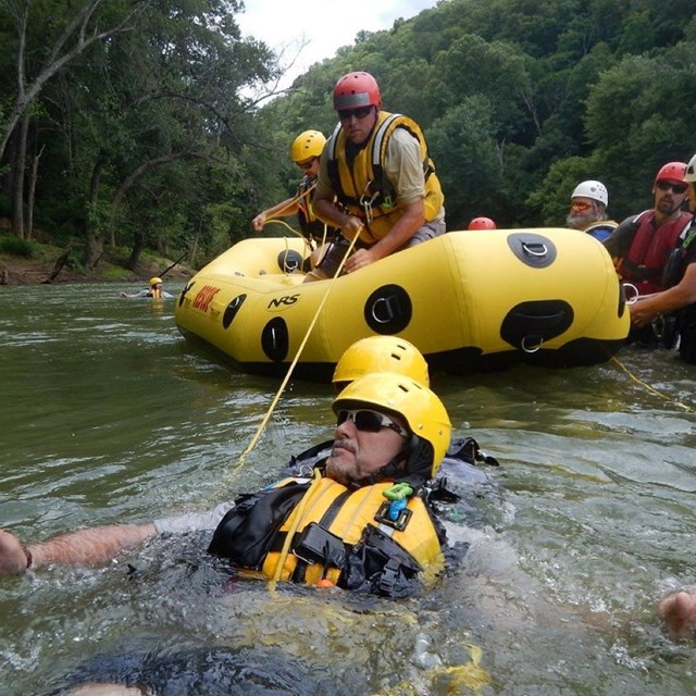 Park personnel in life jackets perform river rescue training.