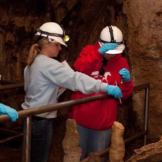 Three teachers in hard hats explore Mammoth Cave.