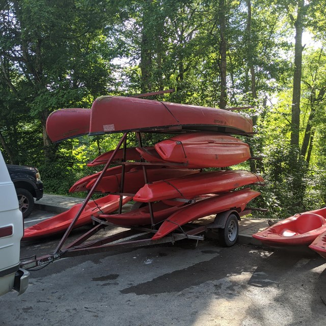 A trailer full of red canoes and kayaks. 