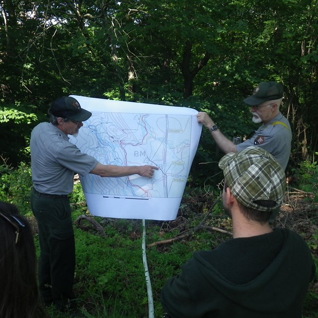 Two park rangers holding up a map.