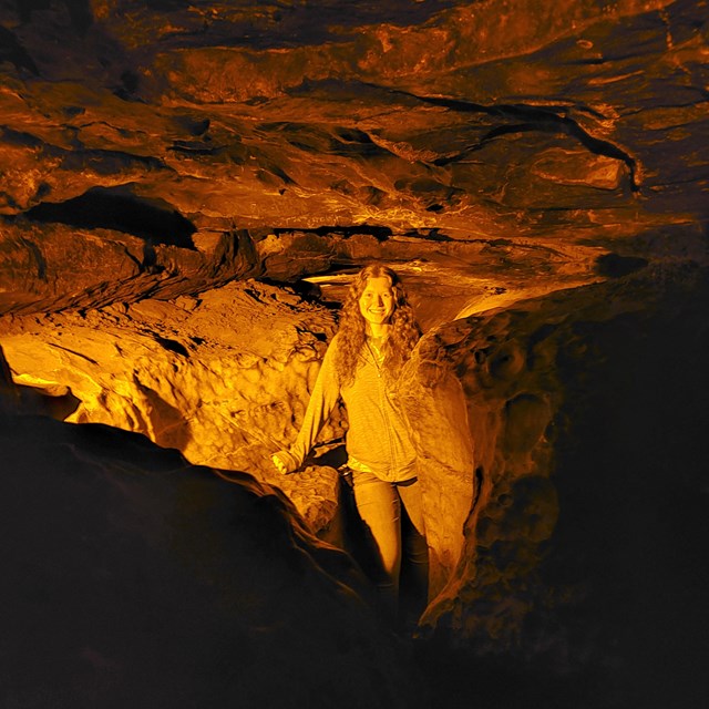 A person standing in a narrow cave passage.