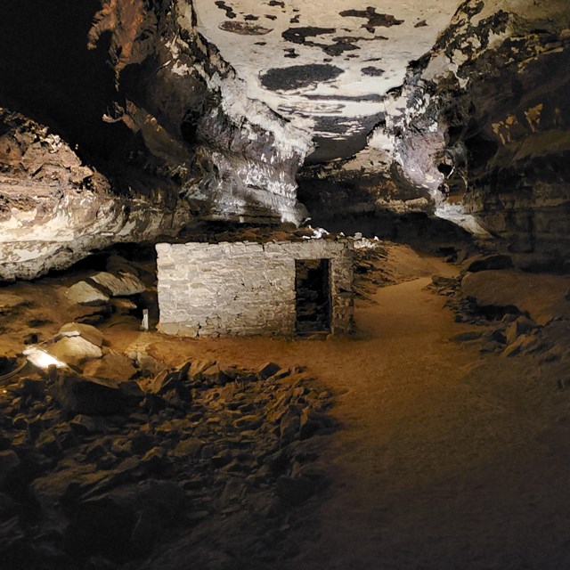 A small stone building inside a cave passage. 