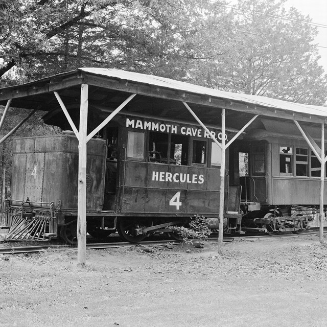 A black and white photo of a small steam engine train. 