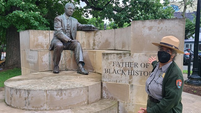 Woman standing outside in front of a statue of Dr. Carter G. Woodson