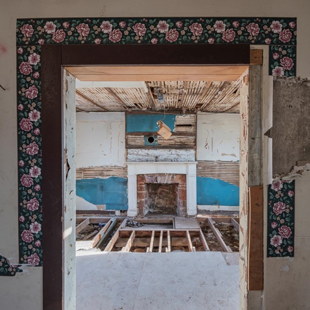 Color photo of the interior of the MJ Dogan house, looking through a doorway into fireplace room